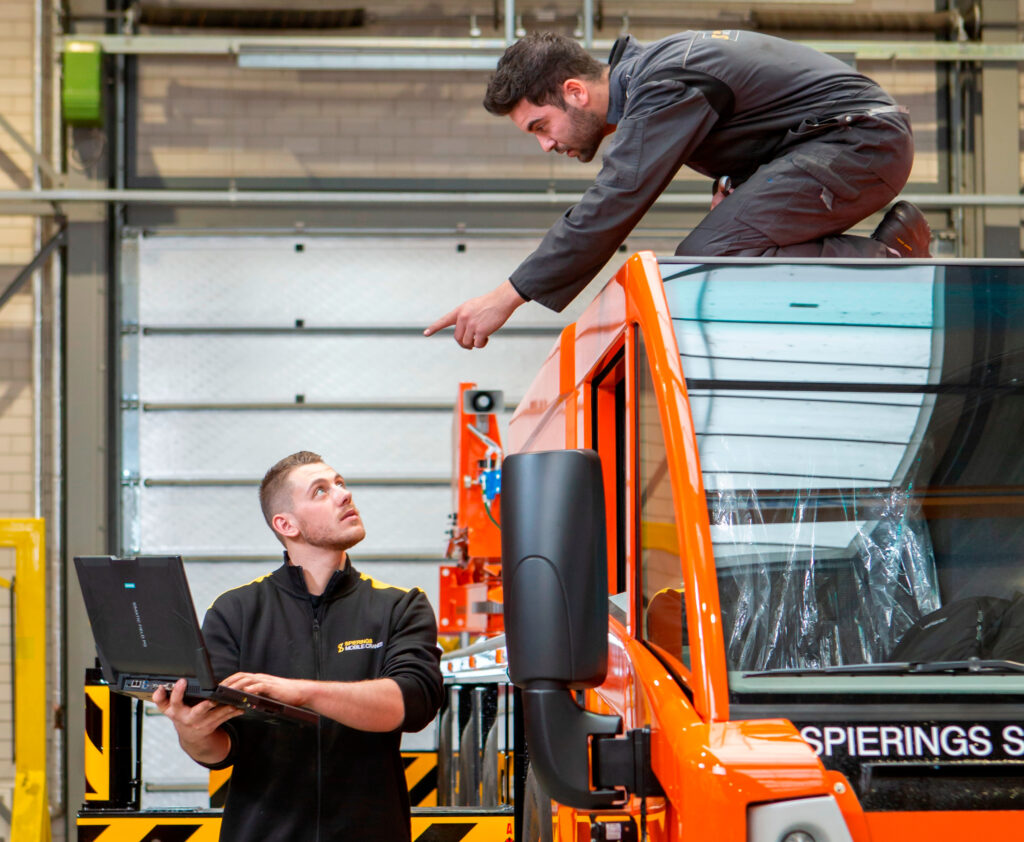 Twee mannen aan het werk in de industrie, een vanaf een auto, de ander met een laptop in de hand