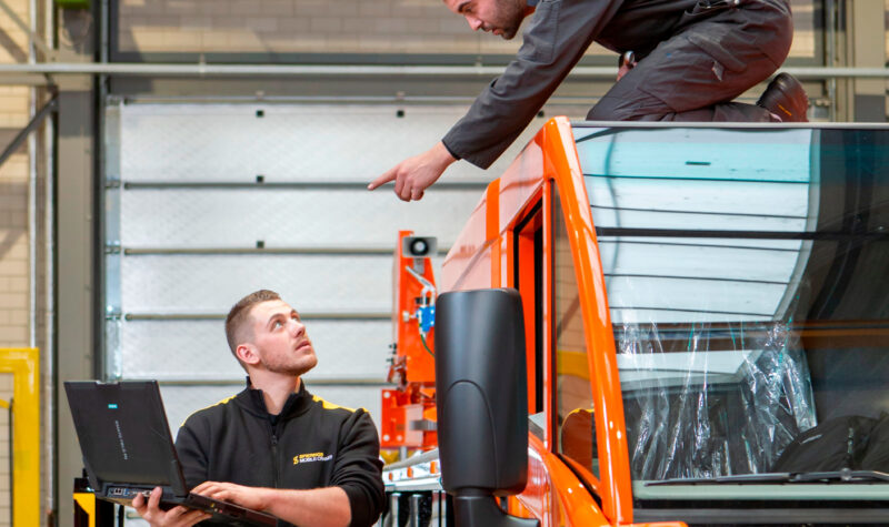 Twee mannen aan het werk in de industrie, een vanaf een auto, de ander met een laptop in de hand