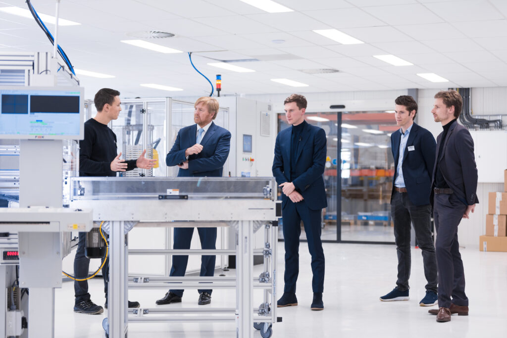 Koning Willem-Alexander krijgt uitleg van een medewerker in de nieuwe batterijfabriek van ELEO