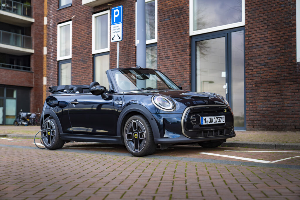 De MINI Cabrio Electric van BMW op een parkeerplaats aan een laadpaal