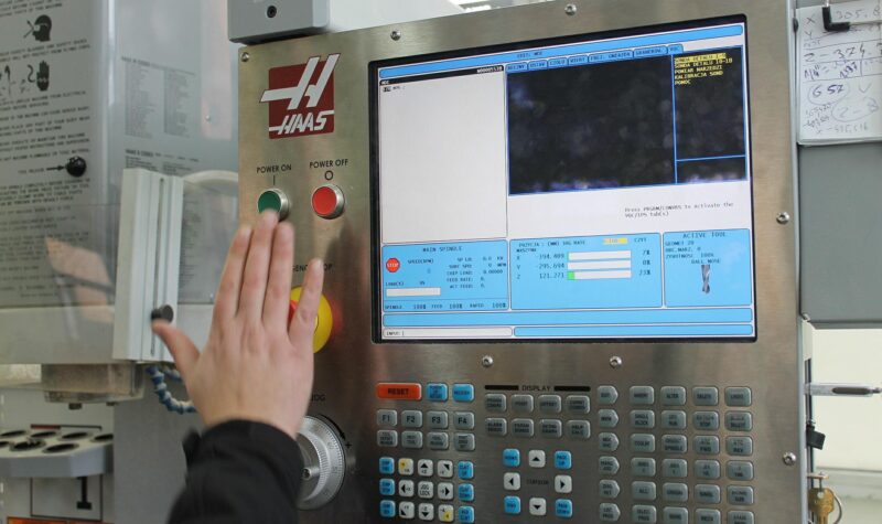 Hand die op een knop druk van een bedieningspaneel in een fabriek