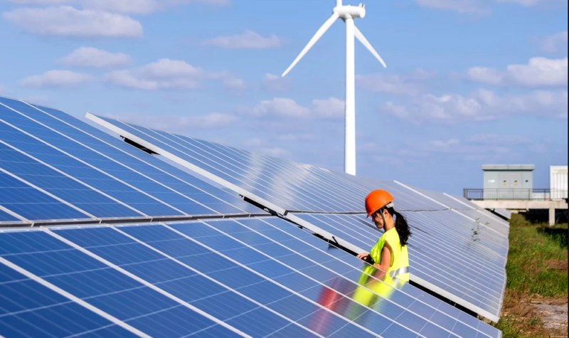 Vrouw met helm op een veld vol zonnepanelen